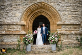   The newlywed couple walk together out of Courteenhall village church, beaming as they step into married life after a ceremony surrounded by loved ones.